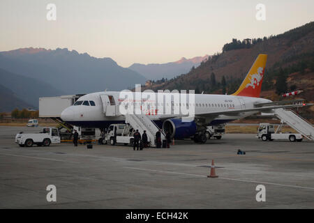 I gestori di bagagli scaricano i bagagli da un aereo Airbus A319-100 di Druk National carrier si trova sul asfalto dell'aeroporto internazionale nella città di Paro in Bhutan Foto Stock