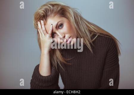 Donna contemplativa in un maglione. Piuttosto giovane donna che guarda sul serio. Foto Stock