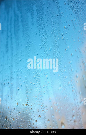 Close up di goccioline di acqua sul vetro della finestra, colori vivaci dal cielo e gli alberi al di fuori del display attraverso l'acqua. Foto Stock