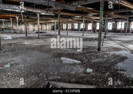 La sala principale in una fabbrica in disuso dove il cotone è stato prodotto, molti tetto tetto metallico supporta, con un sacco di detriti sul terreno Foto Stock