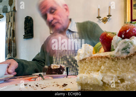 Triste guardando lonesome uomo anziano di mangiare la torta di compleanno a casa da sola in casa sua Foto Stock