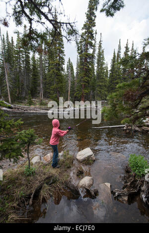 7-anno-vecchia ragazza pesci in un torrente di montagna. Foto Stock