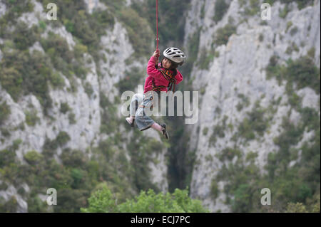 Un 5-anno-vecchia ragazza gode di oscillare in modo sicuro su una fune di arrampicata su una valle profonda. Foto Stock