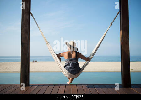 Donna seduta su un hamock in un piccolo hotel nella costa di Oaxaca, Messico. Foto Stock