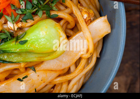 Tirata a mano tesa cinese di spaghetti ramen su una ciotola con baguette Foto Stock