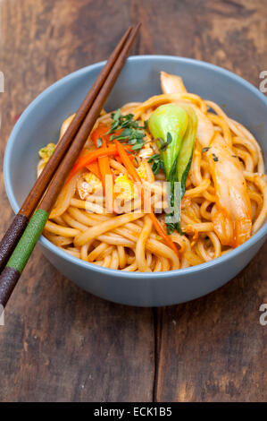 Tirata a mano tesa cinese di spaghetti ramen su una ciotola con baguette Foto Stock