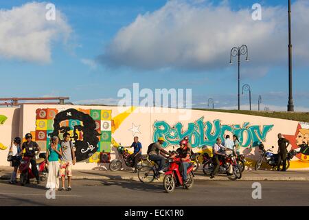 Cuba, La Habana, pedoni, motociclo conducenti e il ciclista di fronte un murale in rappresentanza di Che Guevara (Copyright Alberto Diaz Guttierez alias Korda) vicino al Malecon Foto Stock