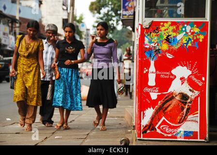 Sri-Lanka, Kandy, le donne a piedi in strada di fronte Coca Cola annuncio Foto Stock