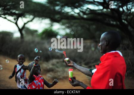 Kenya, Laikipia, IL Ngwesi, uomo Masai soffiare bolle e dei bambini che giocano alla loro cattura Foto Stock