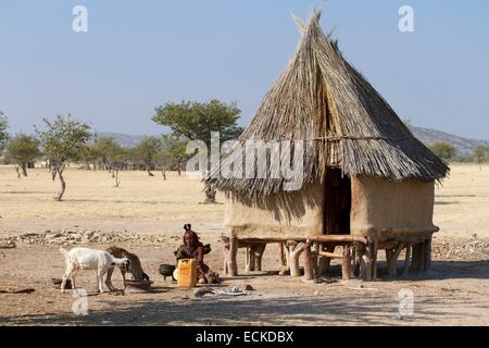 La Namibia, regione di Kunene, Kaokoland, Himba villaggio nei pressi di Opuwo, Himba donna di fronte a una capanna Foto Stock