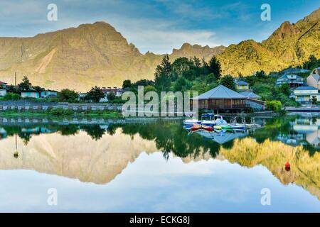 Reunion, il Parc National de la Reunion Reunion (Parco Nazionale), il Cirque de Cilaos, classificato come patrimonio mondiale dall UNESCO, Cilaos, paesaggio montuoso, la riflessione di una montagna ed il Creolo casa su un laghetto di sunrise Foto Stock