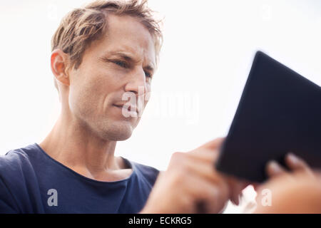 Uomo maturo utilizzando computer tavoletta contro il cielo chiaro Foto Stock