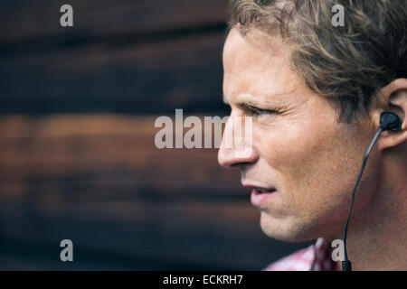 Uomo che indossa un dispositivo vivavoce esterno log cabin Foto Stock