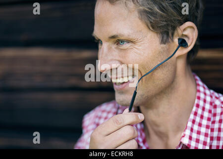 Felice l'uomo utilizzando un dispositivo vivavoce esterno log cabin Foto Stock