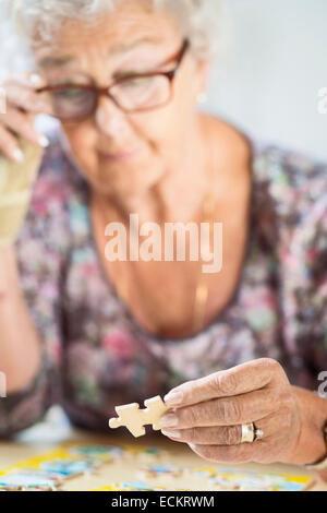 Senior donna risolvendo puzzle a tavola in casa di cura Foto Stock