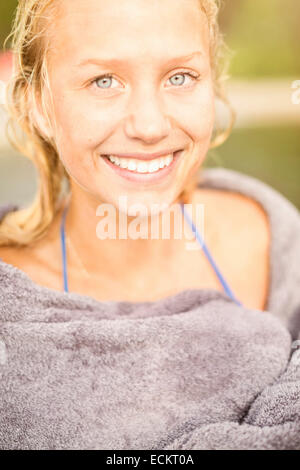 Ritratto di giovane sorridente donna avvolta in asciugamano all'aperto Foto Stock