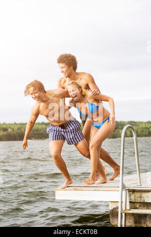 Lunghezza completa di giocosi amici saltando nel lago Foto Stock