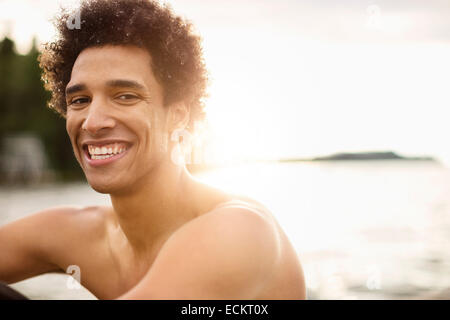 Ritratto di giovane sorridente uomo seduto sul lungolago Foto Stock