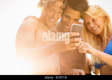 Happy amici utilizzando smart phone contro sky sulla giornata di sole Foto Stock