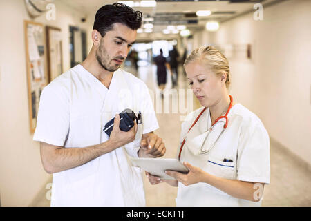 Maschio e femmina medici discutendo su tavoletta digitale nel corridoio di ospedale Foto Stock