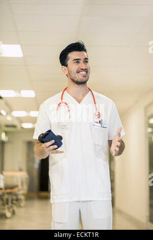 Sorridente giovane maschio medico gesticolando in ospedale Foto Stock