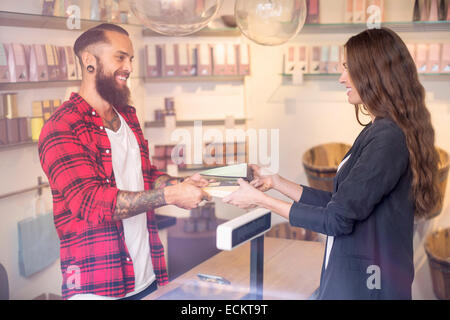 Felice proprietario di dare caramelle ai clienti in negozio Foto Stock