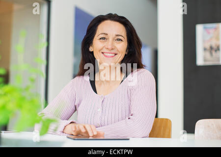 Ritratto di donna felice con tavoletta digitale in casa Foto Stock