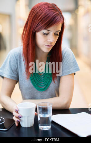 Metà donna adulta libro lettura pur avendo il caffè nel ristorante Foto Stock