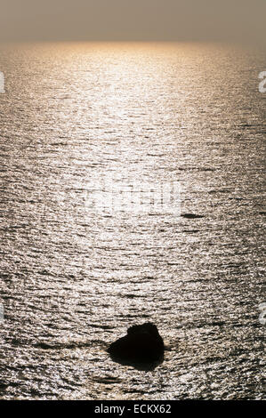 Tramonto sul mare con un lone rock Foto Stock