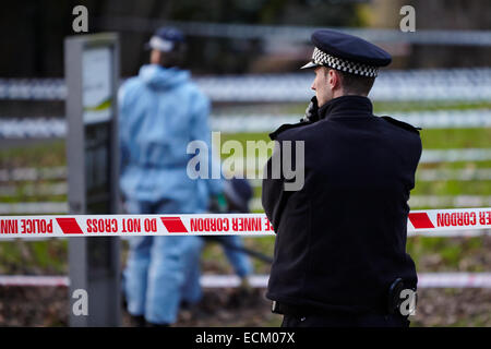 Londra, Regno Unito. Xvi Dec, 2014. Un uomo è stato ucciso nella gamba la scorsa notte (15 dicembre 2014) a circa 23.30 vicino a campi di Highbury park, a seguito di una perturbazione presso il Garage music venue. Scena del crimine gli investigatori (in blu) sono illustrati oggi, ricerca la zona con un rivelatore di metalli. Gli ufficiali di polizia di guardia intorno alla scena del crimine. L'uomo di lesioni non sono pensati per essere un pericolo per la vita. Islington. Londra. Regno Unito. Dicembre 16th, 2014. Credito: Sam Barnes/Alamy Live News Foto Stock