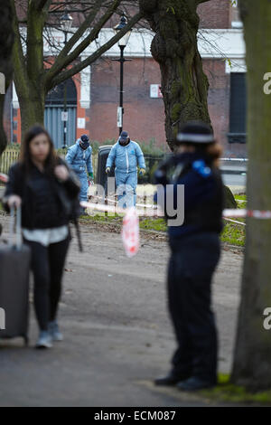 Londra, Regno Unito. Xvi Dec, 2014. Un uomo è stato ucciso nella gamba la scorsa notte (15 dicembre 2014) a circa 23.30 vicino a campi di Highbury park, a seguito di una perturbazione presso il Garage music venue. Scena del crimine gli investigatori (in blu) sono illustrati oggi, ricerca la zona con un rivelatore di metalli. Gli ufficiali di polizia di guardia intorno alla scena del crimine. L'uomo di lesioni non sono pensati per essere un pericolo per la vita. Islington. Londra. Regno Unito. Dicembre 16th, 2014. Credito: Sam Barnes/Alamy Live News Foto Stock