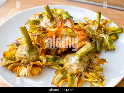 Romana Carciofi fritti (stile ebraico) con scaglie di sale di mare su di un tavolo di legno. Foto Stock