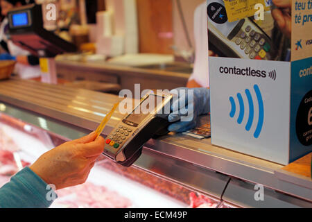 Una donna paga su una macelleria con un credito contactless card sistema nell'isola di Maiorca, SPAGNA Foto Stock