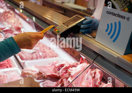 Una donna paga su una macelleria con un credito contactless card sistema nell'isola di Maiorca, SPAGNA Foto Stock