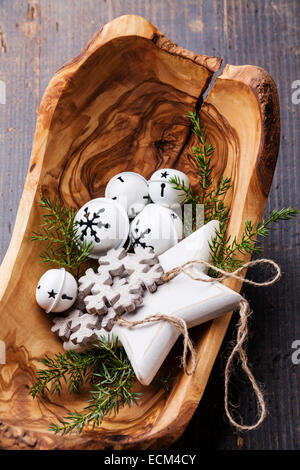 Le decorazioni di Natale le campane in legno d'olivo ciotola sul verde abete rami sullo sfondo Foto Stock