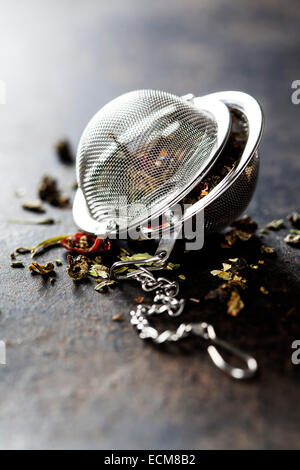 Composizione di tè con filtro di tè su sfondo scuro Foto Stock