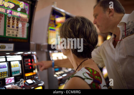 Uomo che spiega la lettura e regole per una donna su macchine di scanalatura in un casinò Repubblica Dominicana Foto Stock