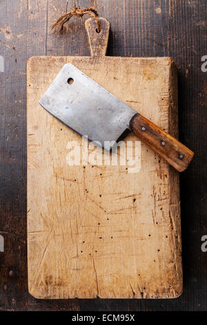 Tagliere e carne cleaver scuro su sfondo di legno Foto Stock