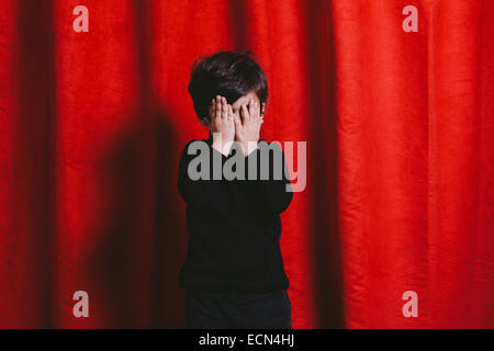 Ritratto in studio di un bambino di tre anni ragazzo con le sue mani sul suo viso Foto Stock