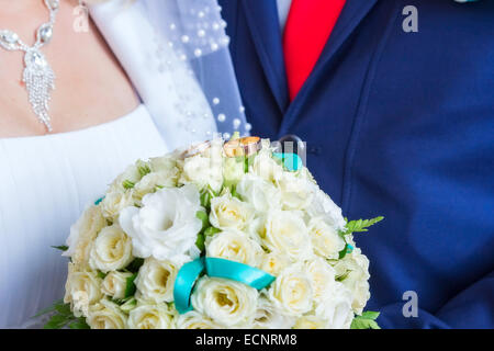 Piccolo bouquet nuziale in mani e gli anelli su di esso Foto Stock