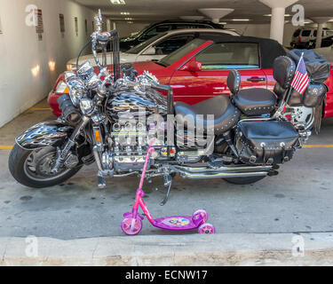 Una Honda Valkyrie motociclo parcheggiato a fianco di un bambini scooter. Foto Stock