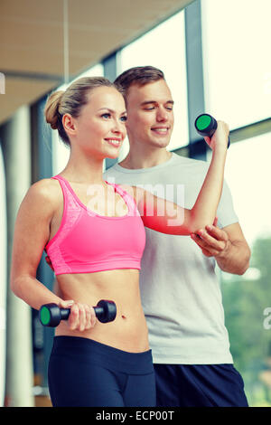 Sorridente giovane donna con personal trainer in palestra Foto Stock