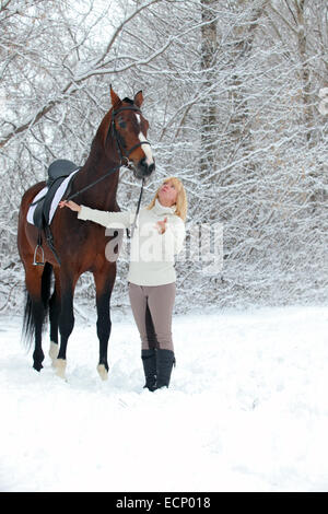 Equitazione donna con il suo cavallo in un paesaggio di neve Foto Stock