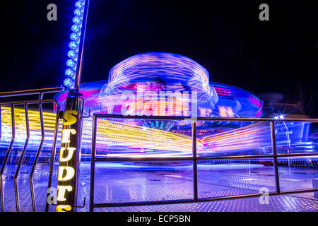 Fiera giostre a Aberystwyth annuale Fiera di Natale la filatura nella notte illuminata dal lampeggiante e luce colorata Foto Stock