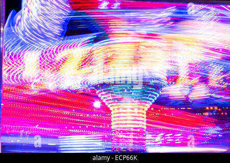 Fiera giostre a Aberystwyth annuale Fiera di Natale la filatura nella notte illuminata dal lampeggiante e luce colorata Foto Stock