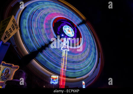Fiera giostre a Aberystwyth annuale Fiera di Natale la filatura nella notte illuminata dal lampeggiante e luce colorata Foto Stock