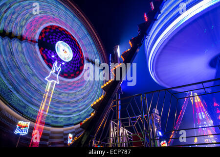 Fiera giostre a Aberystwyth annuale Fiera di Natale la filatura nella notte illuminata dal lampeggiante e luce colorata Foto Stock