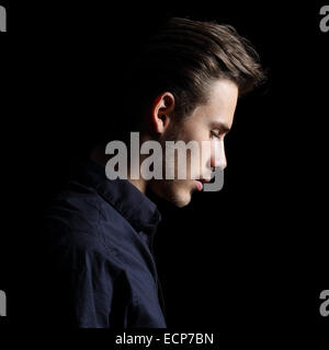 Profilo di un uomo triste faccia crestfallen su isolato nero su sfondo nero Foto Stock