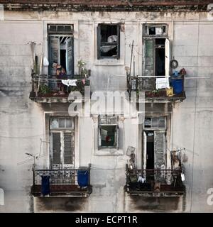 Una donna cubana pulisce il balcone del suo appartamento a l'Avana, Cuba. Foto Stock