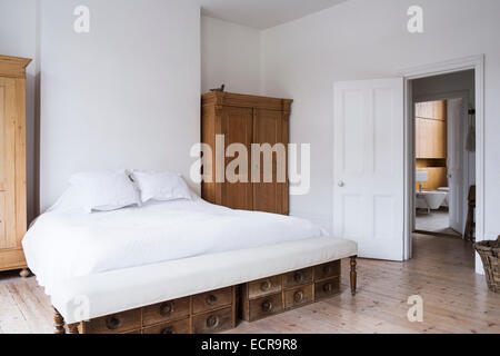 Grande letto bianco in bianco minimo camera da letto con armadi in legno e pavimenti Foto Stock